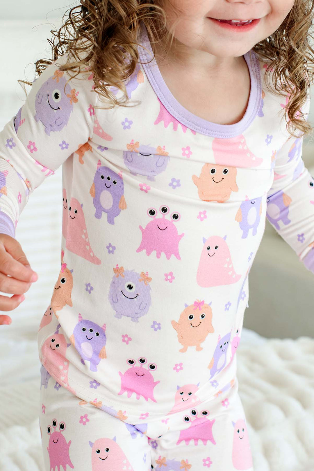 Close-up of a toddler's torso and shoulders showing the neckline and print detail of a Caden Lane Little Monsters two-piece pajama set