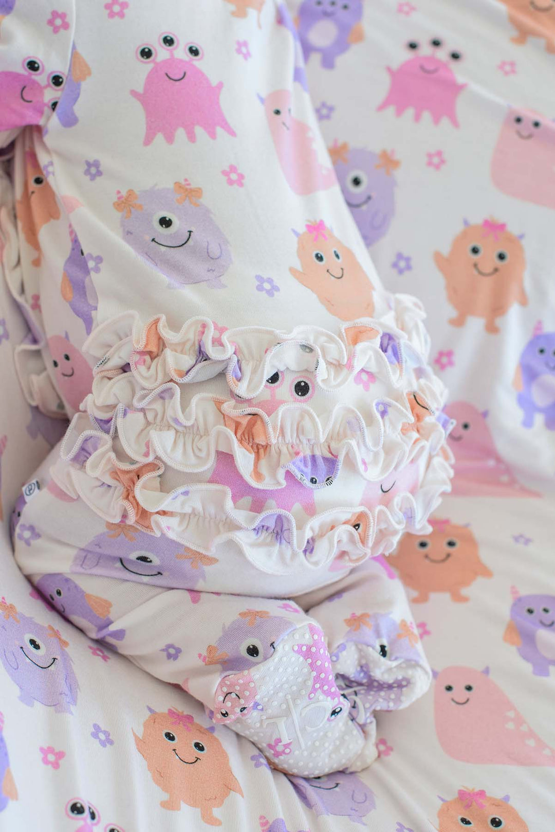 Close-up back view of a newborn wearing a Caden Lane Little Monsters ruffle footie, showing the triple ruffle seat detail