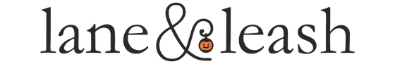 Lane & Leash Halloween themed logo. Text in black reading "lane&leash" with a pumpkin in the middle.
