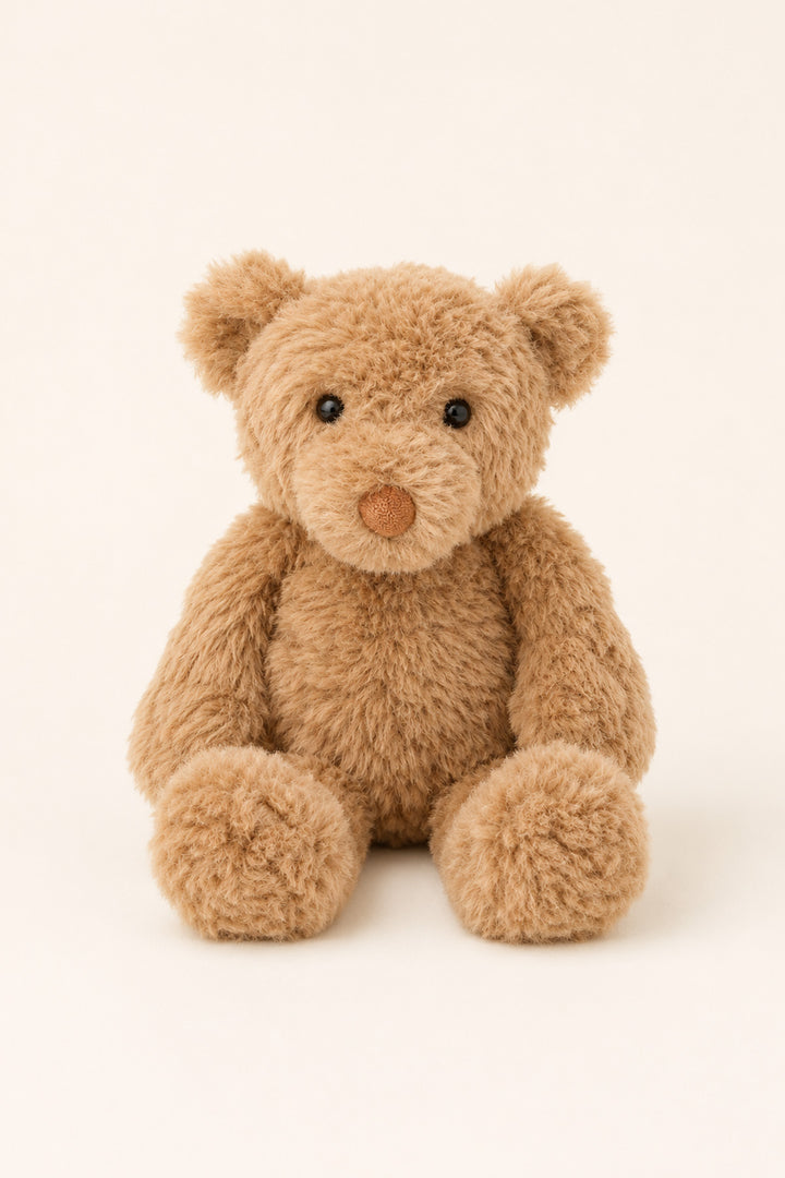 A plush teddy bear made of soft, curly light brown faux fur, sitting against a solid off-white background.