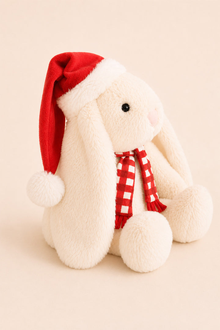 A Caden Lane cream-colored plush bunny doll wearing a red Santa hat with white trim and a red-and-white checkered scarf, posed against a soft beige background.