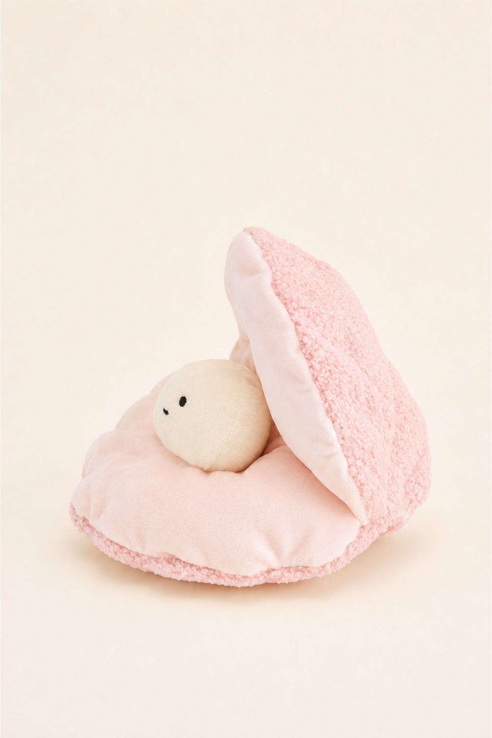 A Caden Lane cute plush toy featuring a small white bear with a black embroidered face nestled inside an open pink teddy shell, set against a solid cream background.