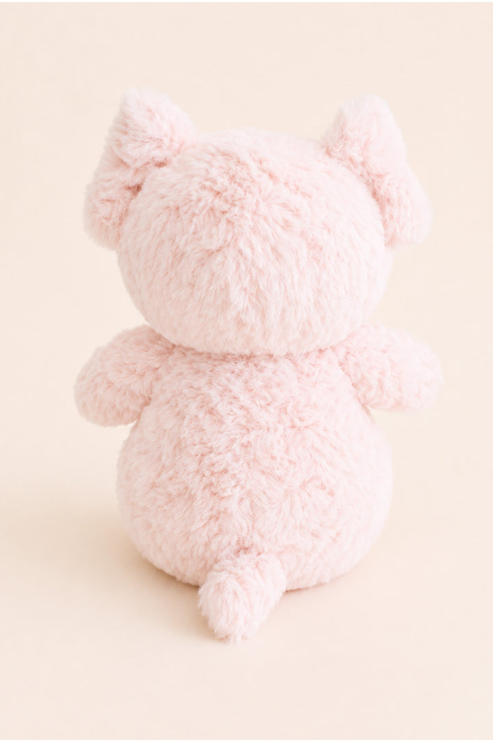 A Caden Lane light pink plush toy shaped like a pig, shown from the back against a solid pale beige background.