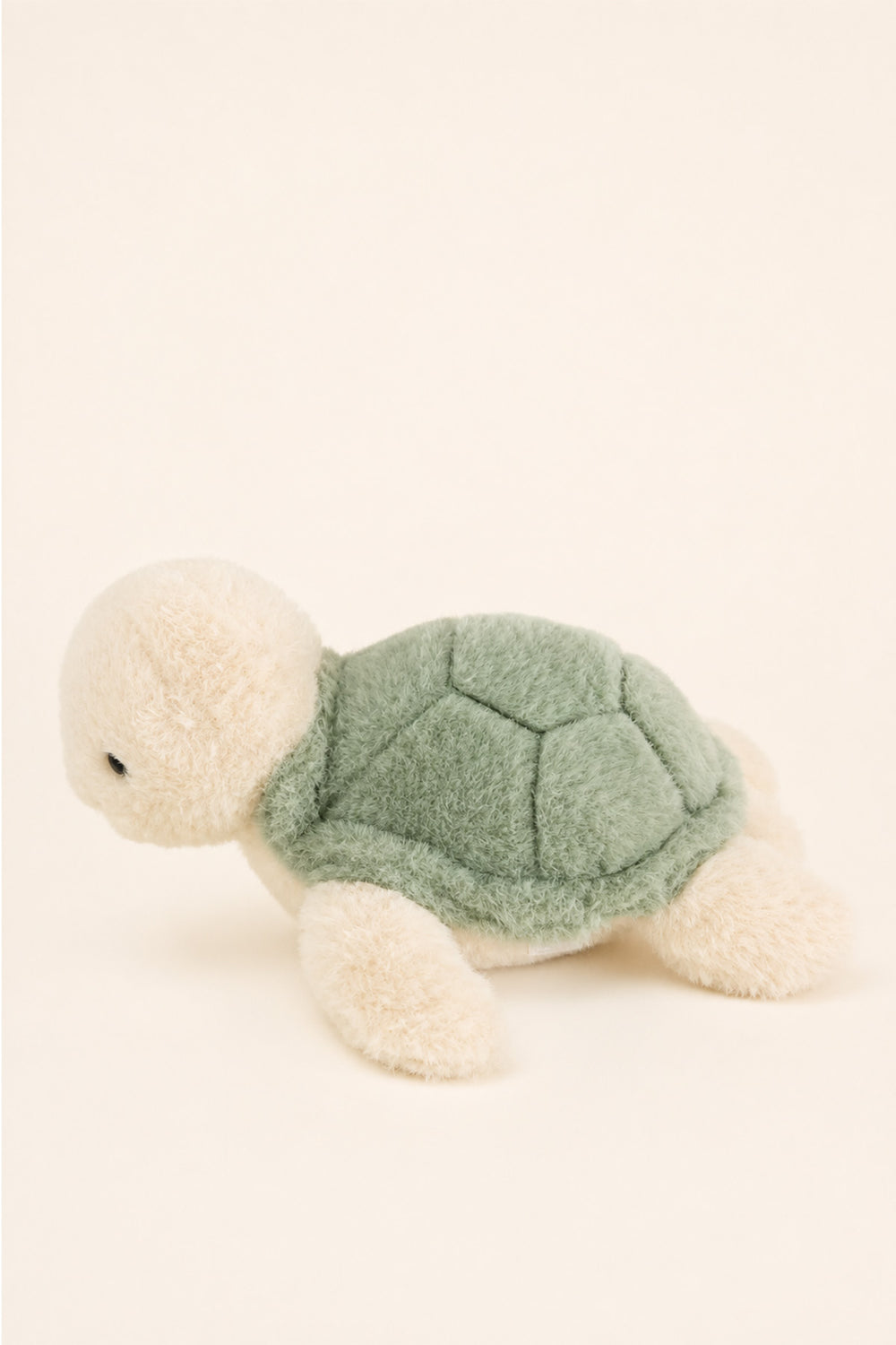 A Caden Lane plush sea turtle toy with a textured sage green shell and cream-colored head, legs, and feet, photographed on a solid cream background.