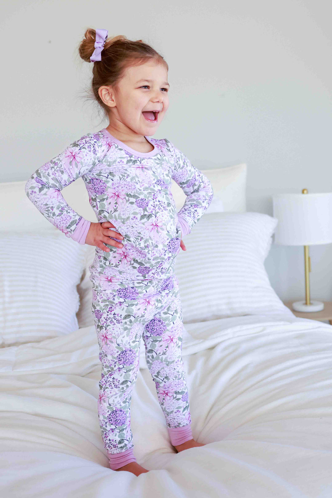girl standing on bed wearing the lavender lullaby two piece pajama set 