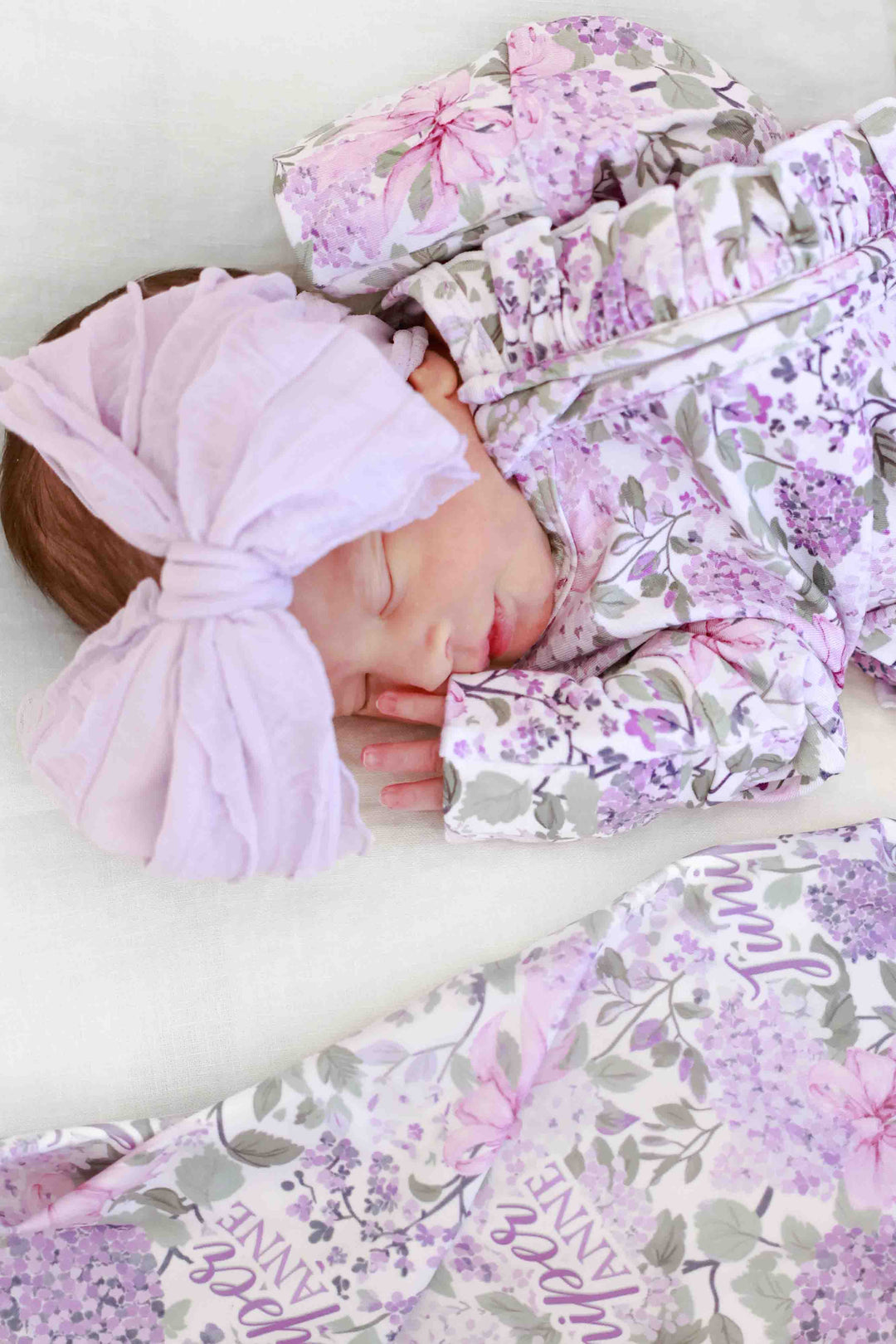 baby girl wearing ruffle knit bow in purple with lavender lullaby ruffle zipper footie