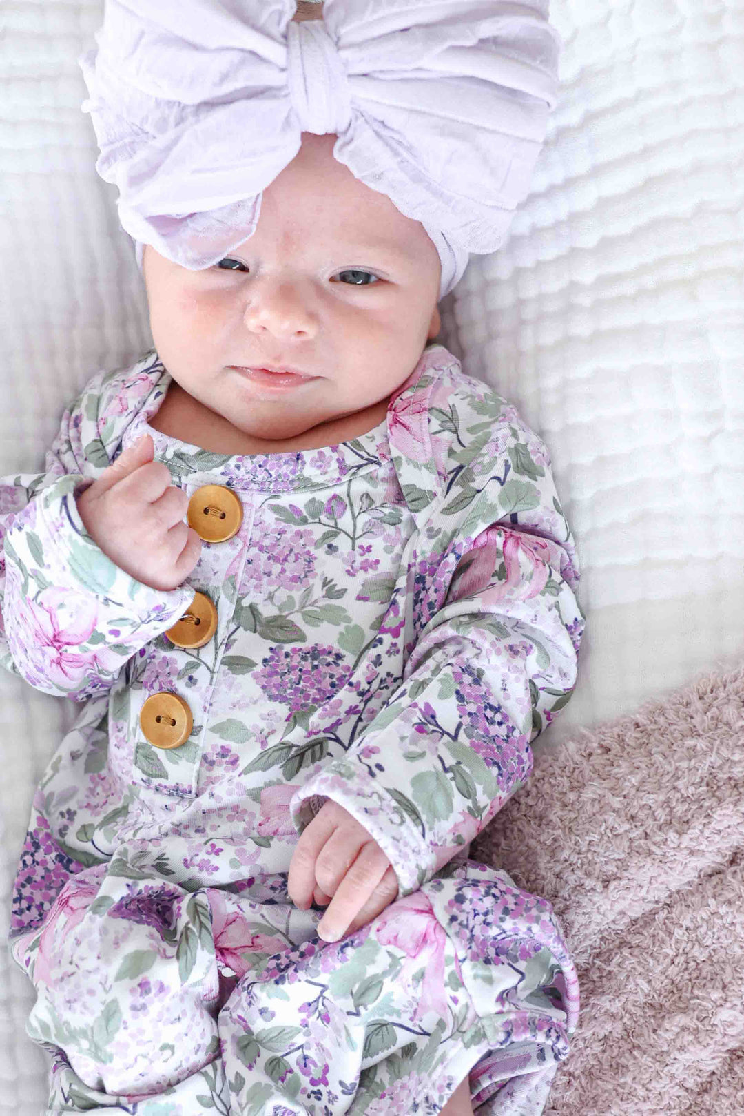 baby girl wearing the lavender lullaby newborn knot gown with a purple ruffle bow