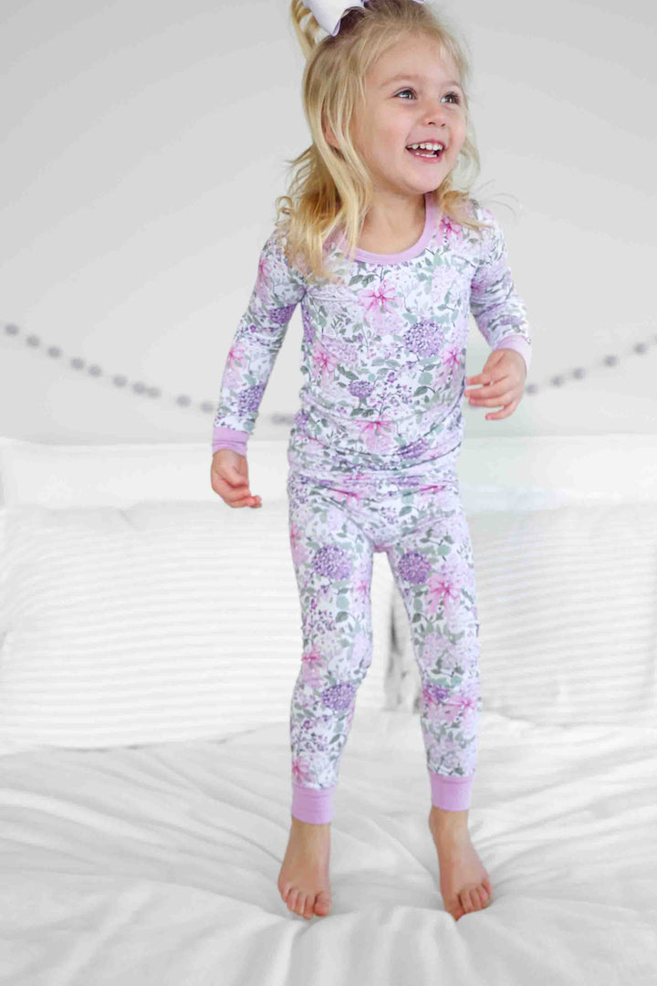girl jumping on bed in lavender lullaby two piece pajama set