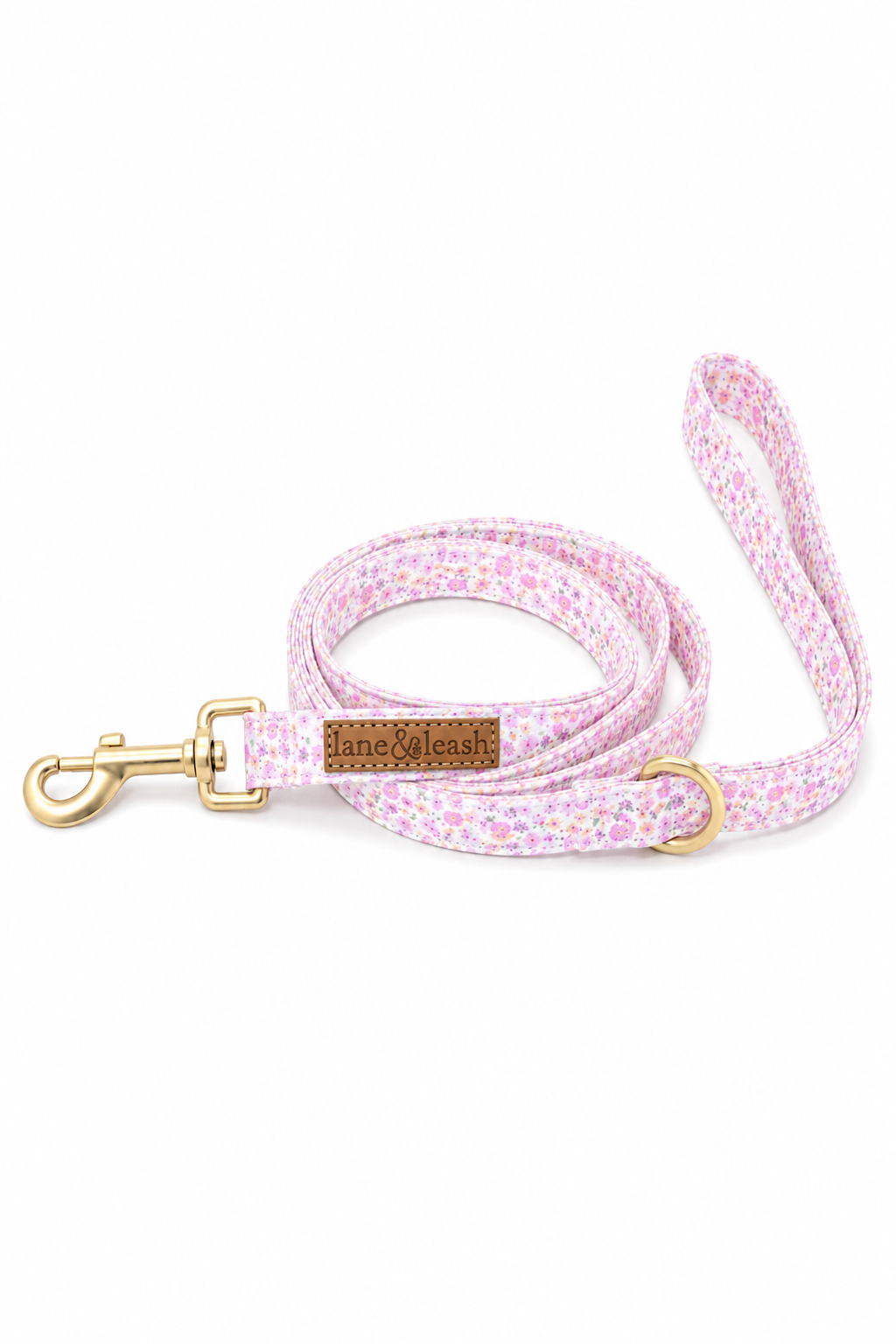 Coiled Scattered Blooms dog leash with pink ditsy floral print, gold snap hook, D-ring for waste bag holder, and Lane & Leash leather logo tag