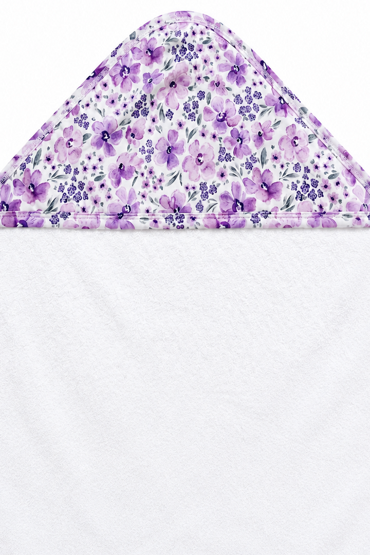 Flat lay of the hood on a Caden Lane white terry baby hooded towel with printed trim in a Lilac Dreams print featuring lavender blooms and tiny violet florals.