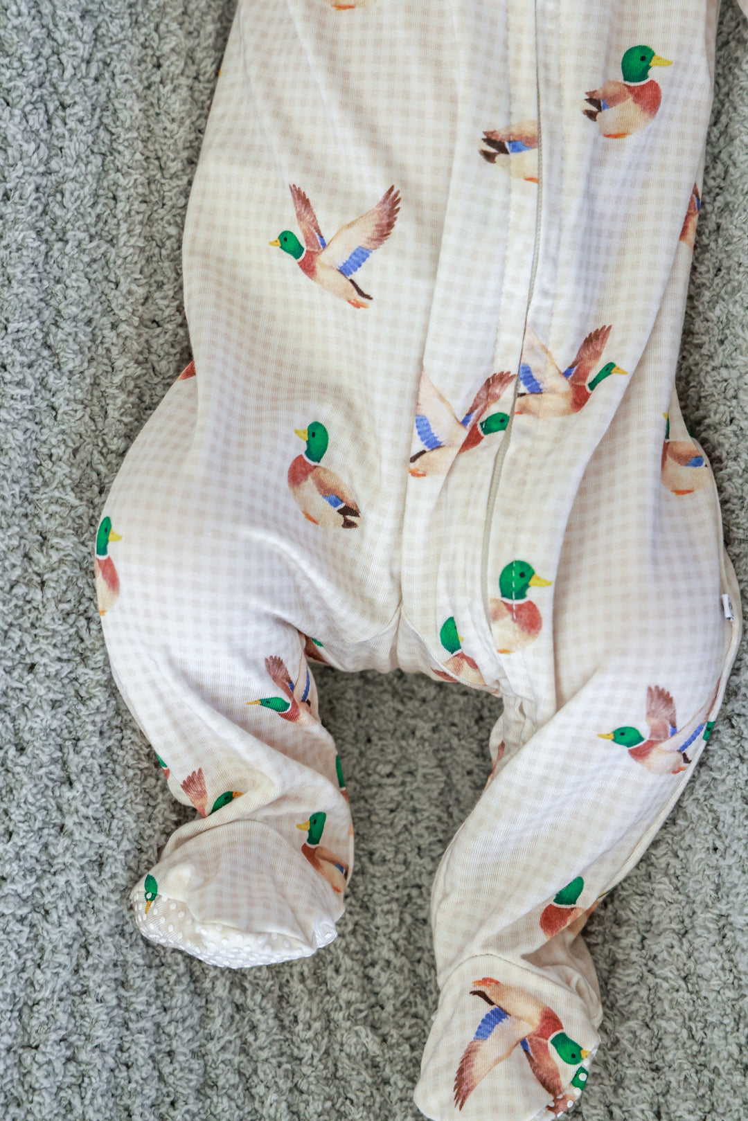 Close-up of baby's legs and feet in little mallard duck print bamboo zipper footie showing the built-in foot coverage and duck print