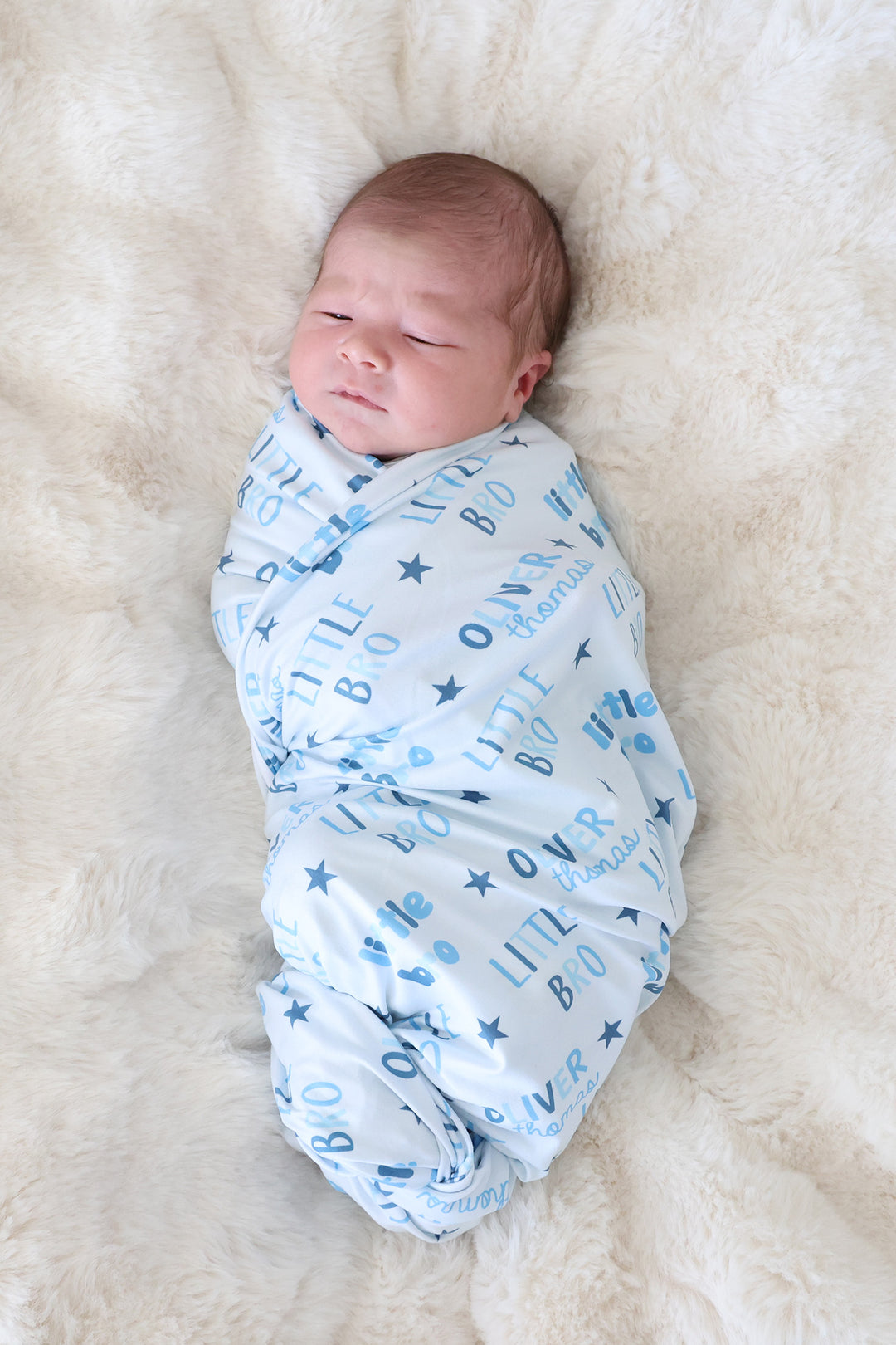 newborn boy wrapped in little bro personalized swaddle blanket blue with stars 