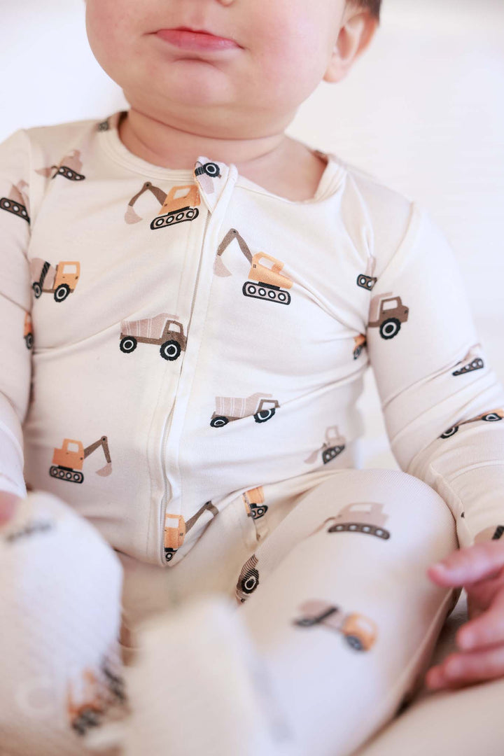 closeup of bamboo zipper footie in little builder print 