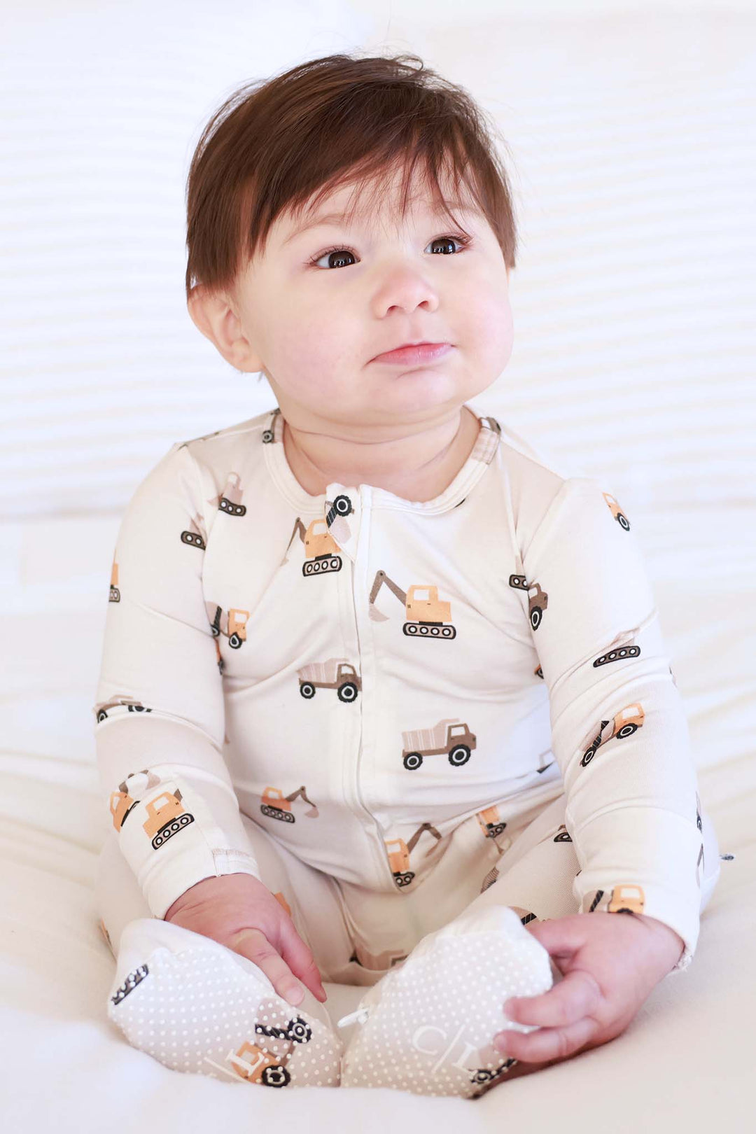 sitting baby boy in little builder cream zipper footie pajama 
