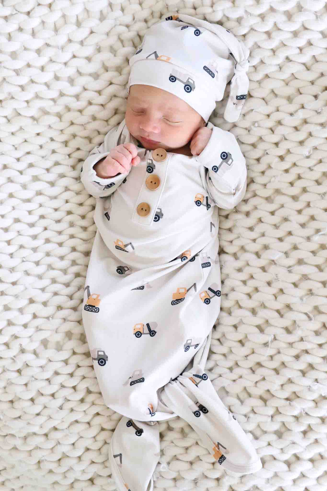 newborn boy laying on neutral blanket in little builder knot gown