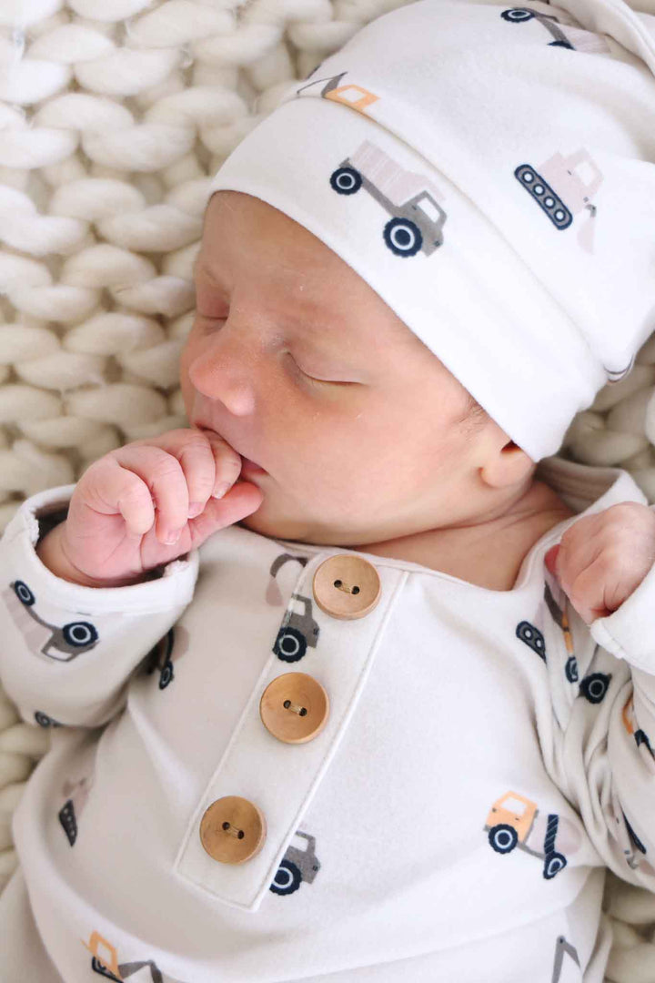 closeup of baby boy wearing neutral construction themed romper