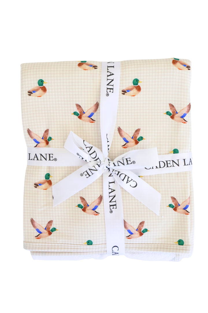 Close-up of folded little mallard duck print bamboo fabric tied with a white Caden Lane ribbon bow, showing vibrant mallard duck pattern
