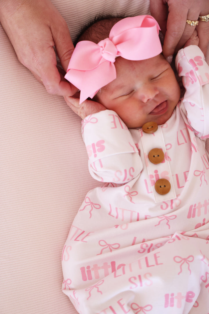 closeup of cuffs on little sis pink newborn knot gown with matching ribbon bow headband 