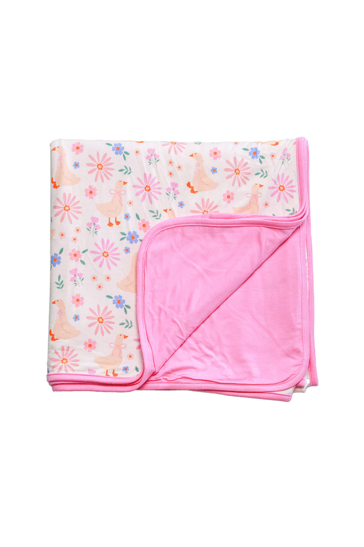 Double Sided Bamboo Blanket in the Lucy Goosy floral print folded to show the corner, revealing the pink solid bamboo reverse side on a white background