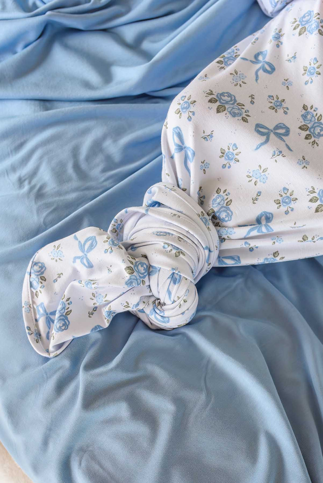 Close-up of the knotted hem of a Tied In Blooms knot gown in blue floral and bow print