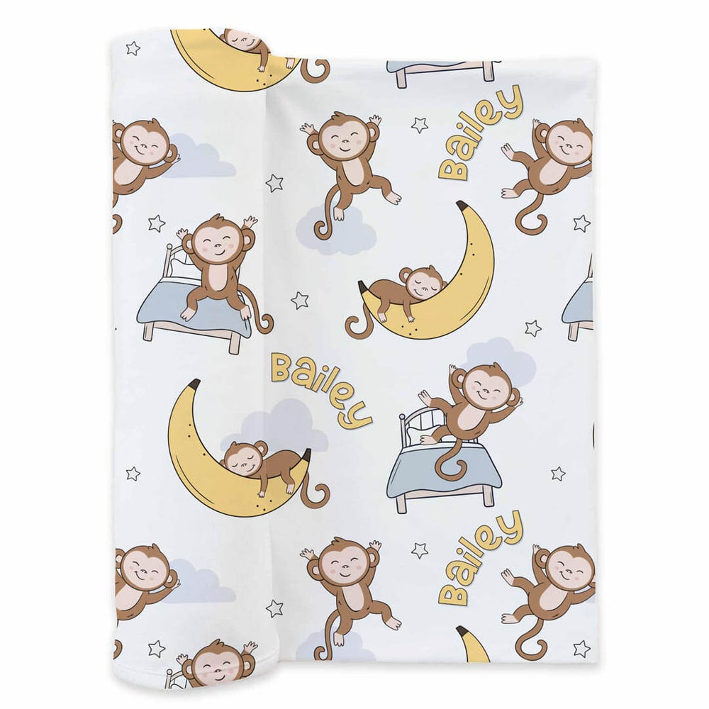 personalized swaddle blanket with a sleeping monkey laying on a banana moon and jumping on the bed 