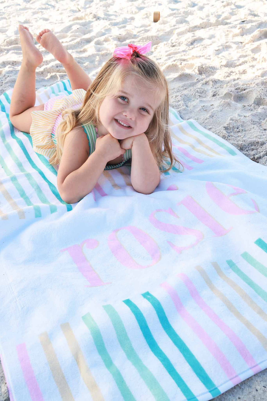 girl laying on beach towel personalized with name and colorful stripes 