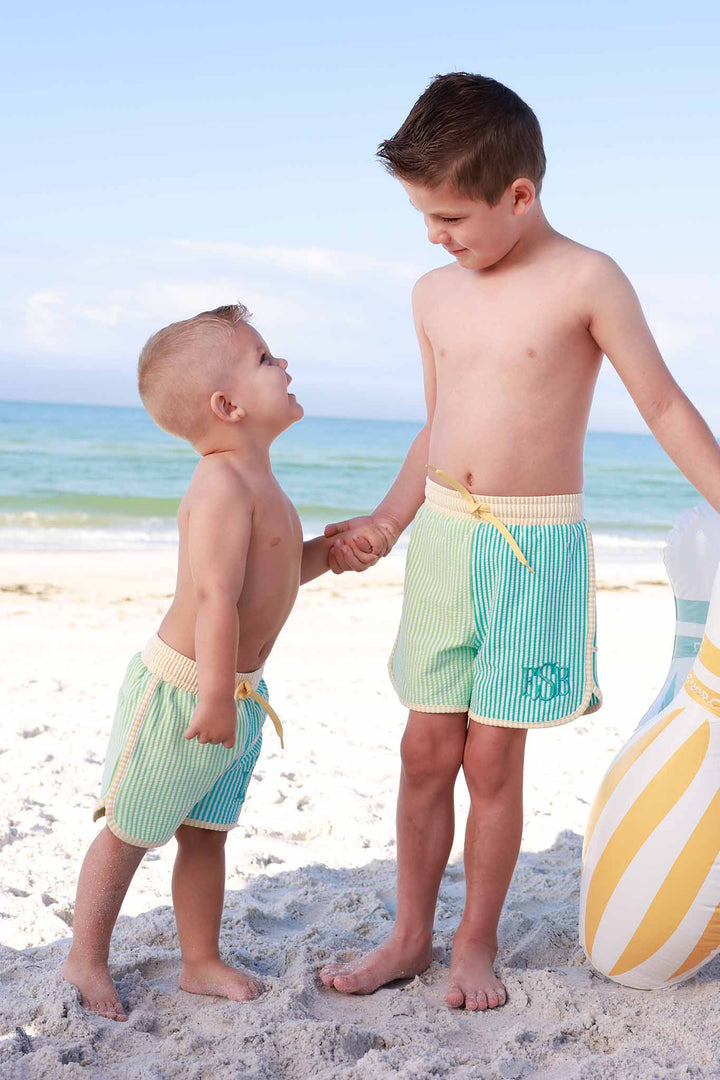 brothers wearing matching monogrammed swim trunks on the beach 