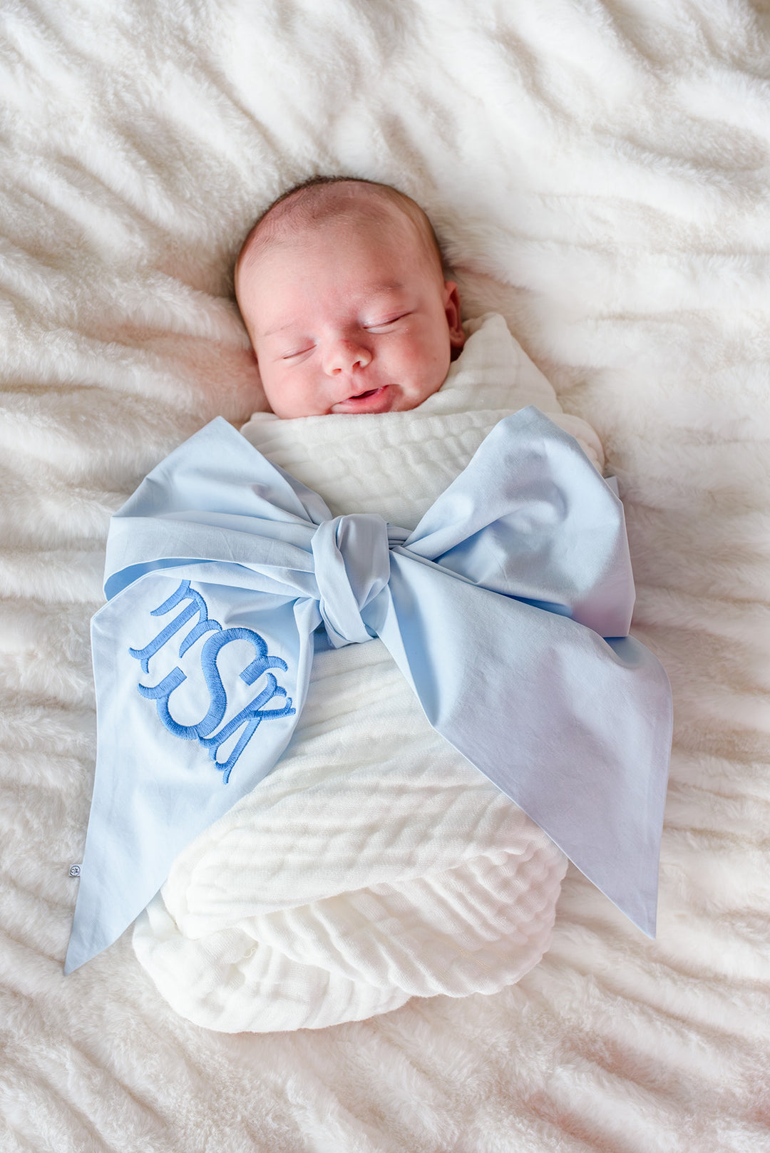 smiling baby boy in light blue monogrammed bow sash 