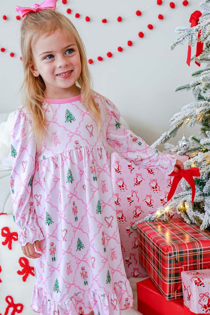 Girl in a Caden Lane pink nutcracker and ballet-print nightgown standing beside wrapped Christmas presents