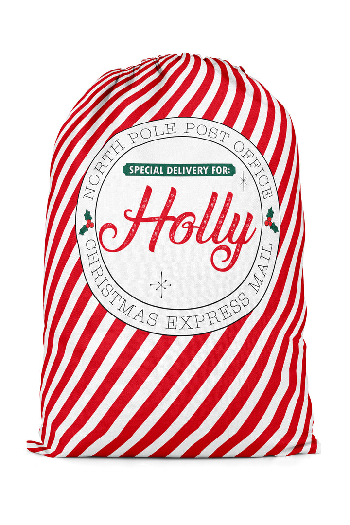 A red and white striped Caden Lane Christmas santa sack with a circular white label reading 'North Pole Post Office' and 'Special Delivery for Holly'.