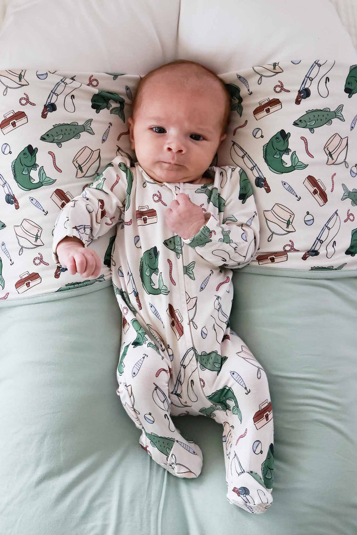 Newborn lying on the Off The Hook double sided bamboo blanket with fishing themed print wearing matching footie