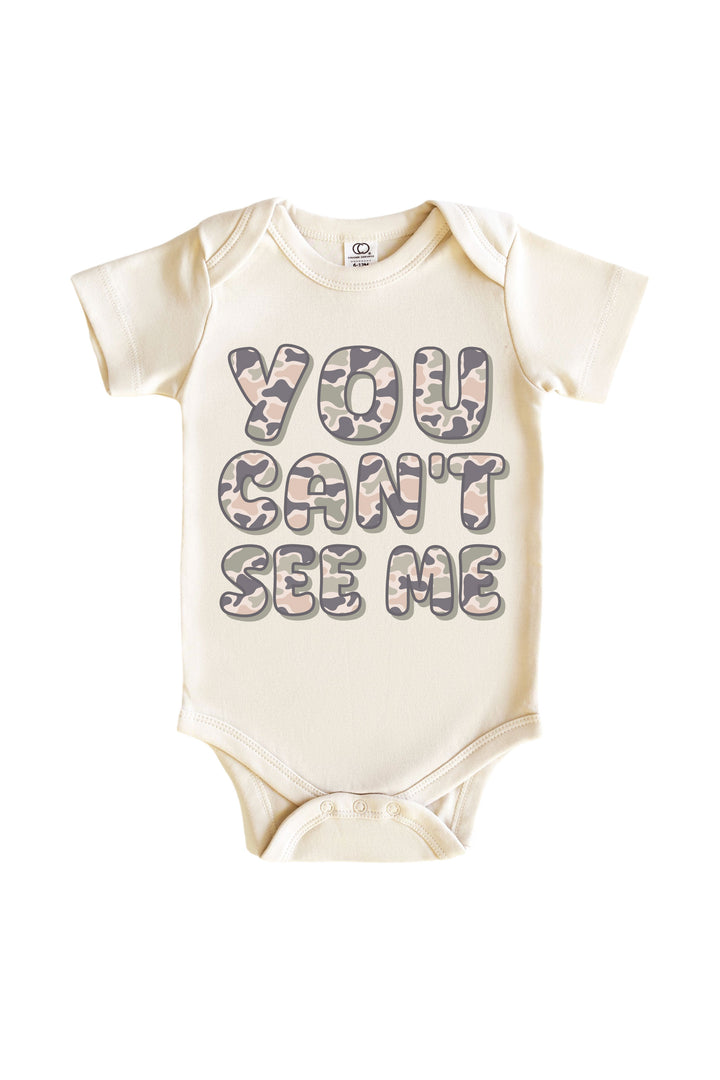 Natural cream baby onesie bodysuit with "You Can't See Me" camo print block lettering on chest