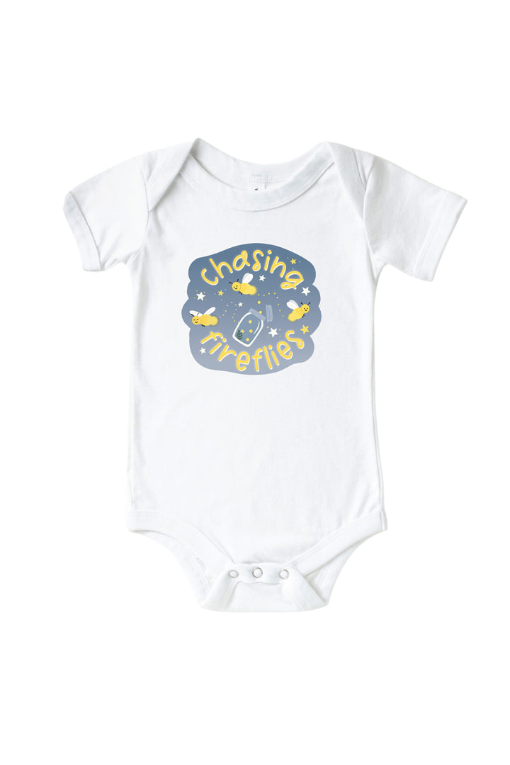 Front view of a Caden Lane white short-sleeve graphic bodysuit with a "Chasing Fireflies" graphic featuring yellow fireflies, stars, and a mason jar on a slate-blue badge.