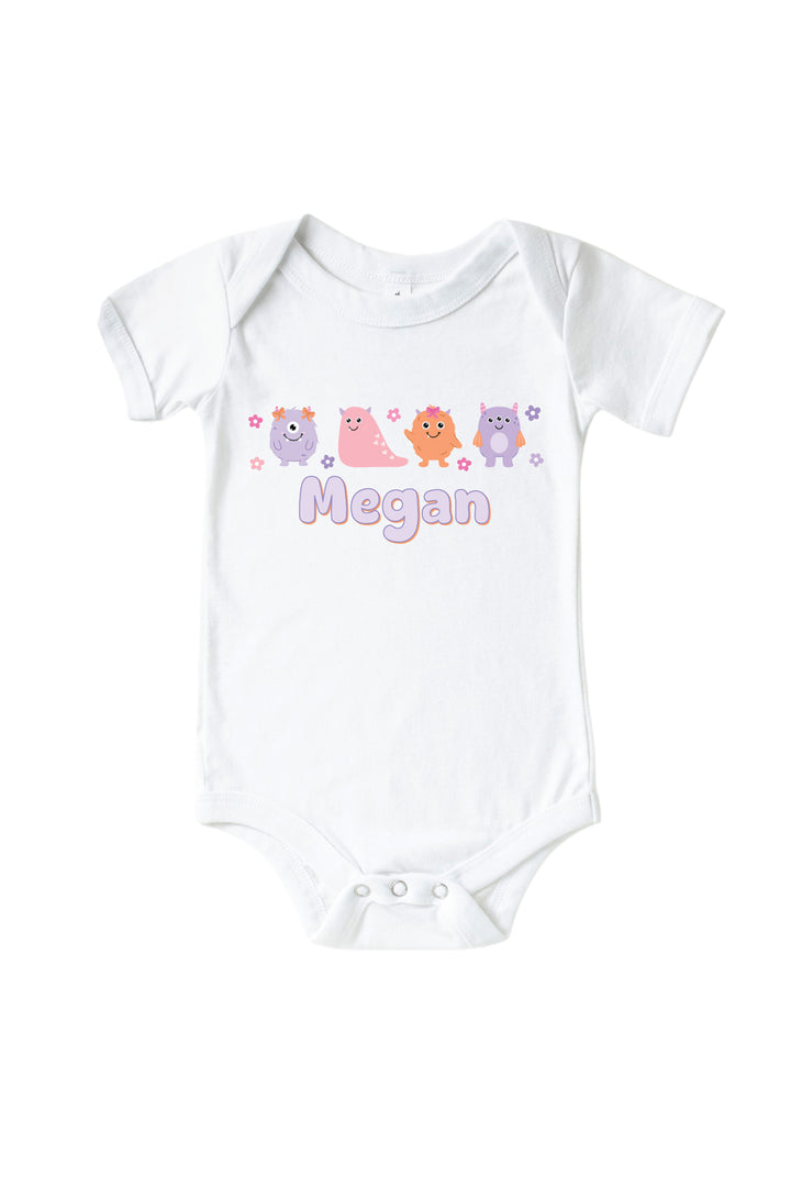 Caden Lane white baby onesie personalized with "Megan" in purple lettering, featuring pink, purple, and orange cartoon monsters and flowers