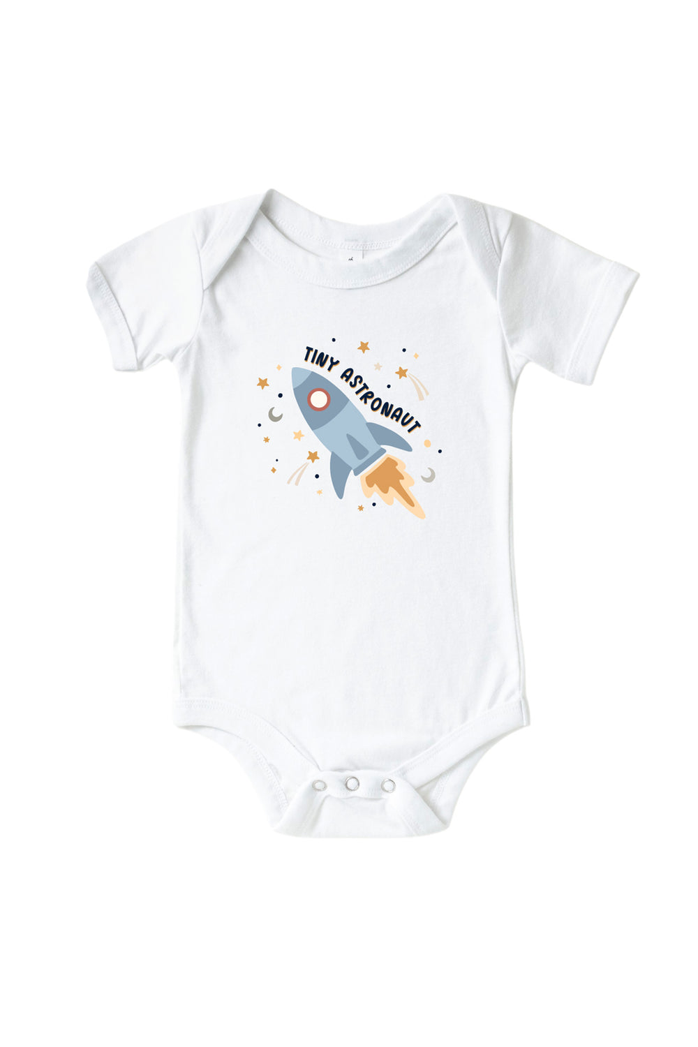 Flat lay of a Caden Lane white short-sleeve bodysuit with a Stellar Snuggles graphic featuring a blue rocket among stars and moons, reading “Tiny Astronaut.”