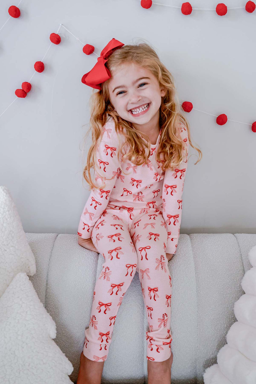 Smiling girl wearing the Caden Lane Peppermint Bows Bamboo Waffle Two-Piece Pajama Set, featuring festive peppermint bows and candy canes on ultra-soft bamboo viscose waffle knit for cozy Christmas sleepwear.