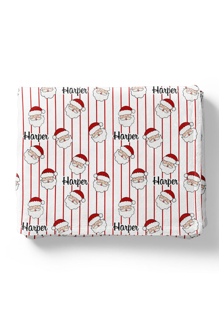 Caden Lane personalized plush baby blanket featuring a festive Santa stripe print with custom name, made for cozy naps, stroller rides, and holiday gifting.