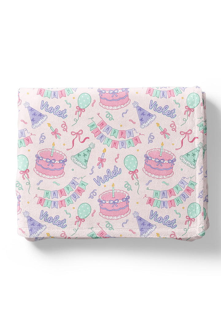 A Caden Lane personalized and colorful 'Violet' birthday pattern with illustrations of cakes, balloons, party hats, banners, and confetti.