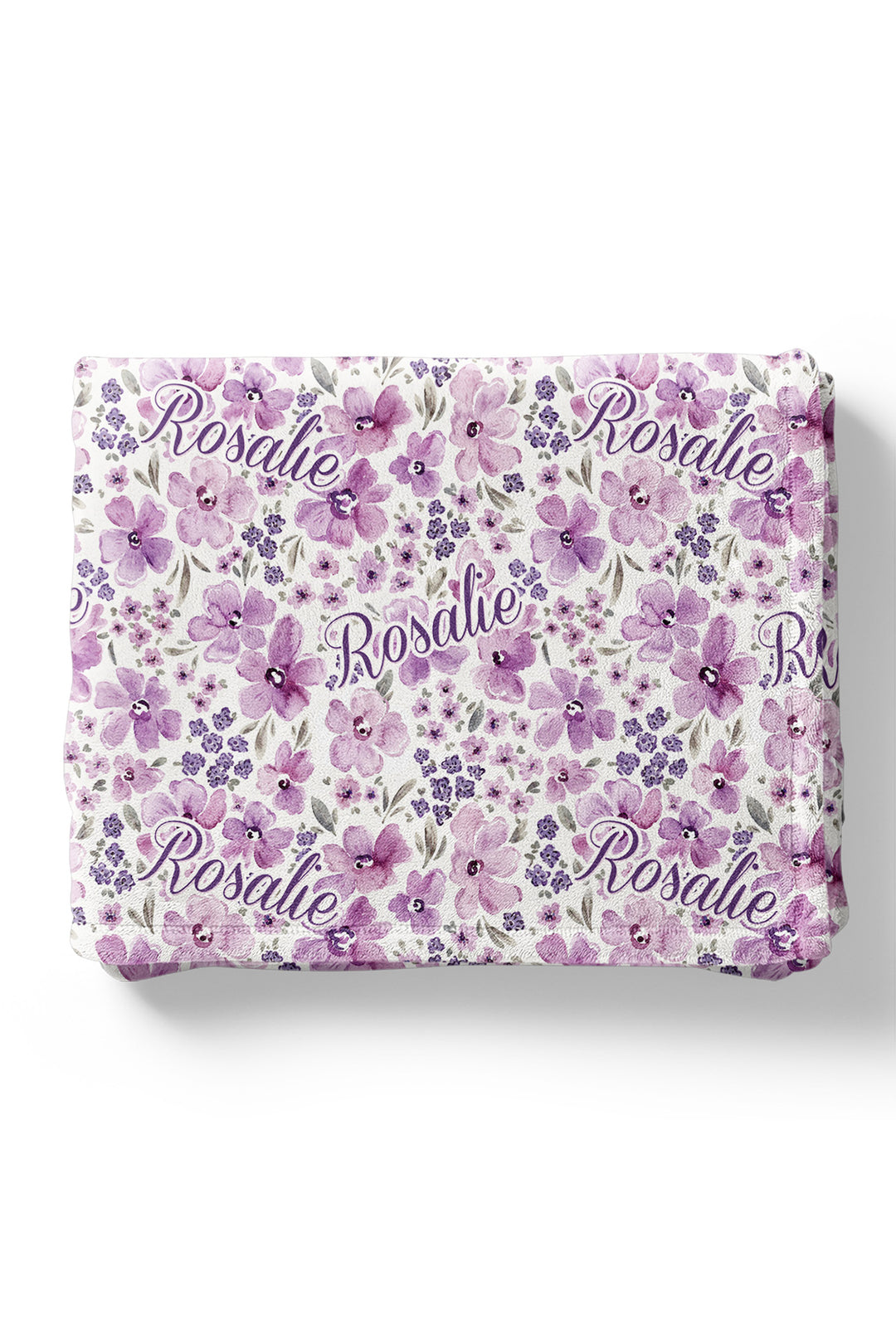 Flat lay of a neatly folded Caden Lane white plush blanket in a Lilac Dreams print featuring lavender blooms and tiny violet florals, reading "Rosalie."