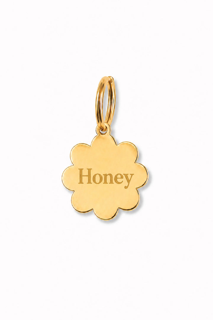 Gold flower-shaped engraved pet ID tag with sample name "Honey" and gold O-ring, on white background