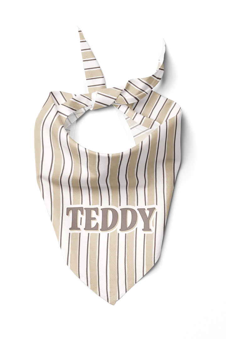 Personalized pet bandana in Biscuit Stripe pattern, tied in a knot, with the name TEDDY embroidered in block letters on the front