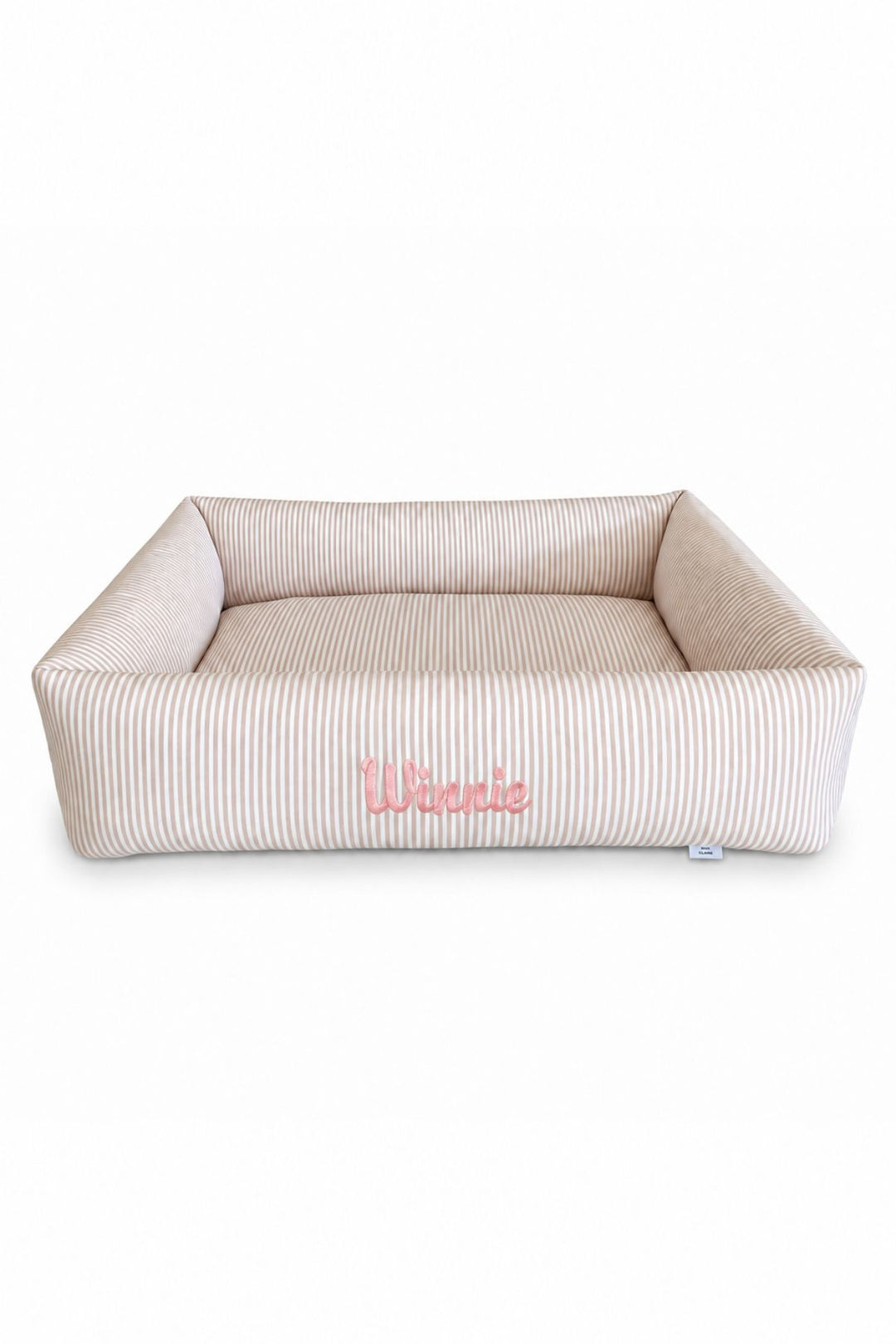 A rectangular cushioned Lane & Leash pet bed with a beige and white vertical stripe pattern, featuring the name 'Winnie' embroidered in pink on the front, set against a plain white background.