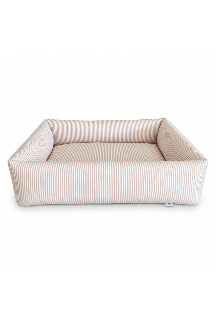 A Lane & Leash rectangular dog bed with a high bolster wall, upholstered in a beige and white vertically striped fabric, shown against a plain white background.