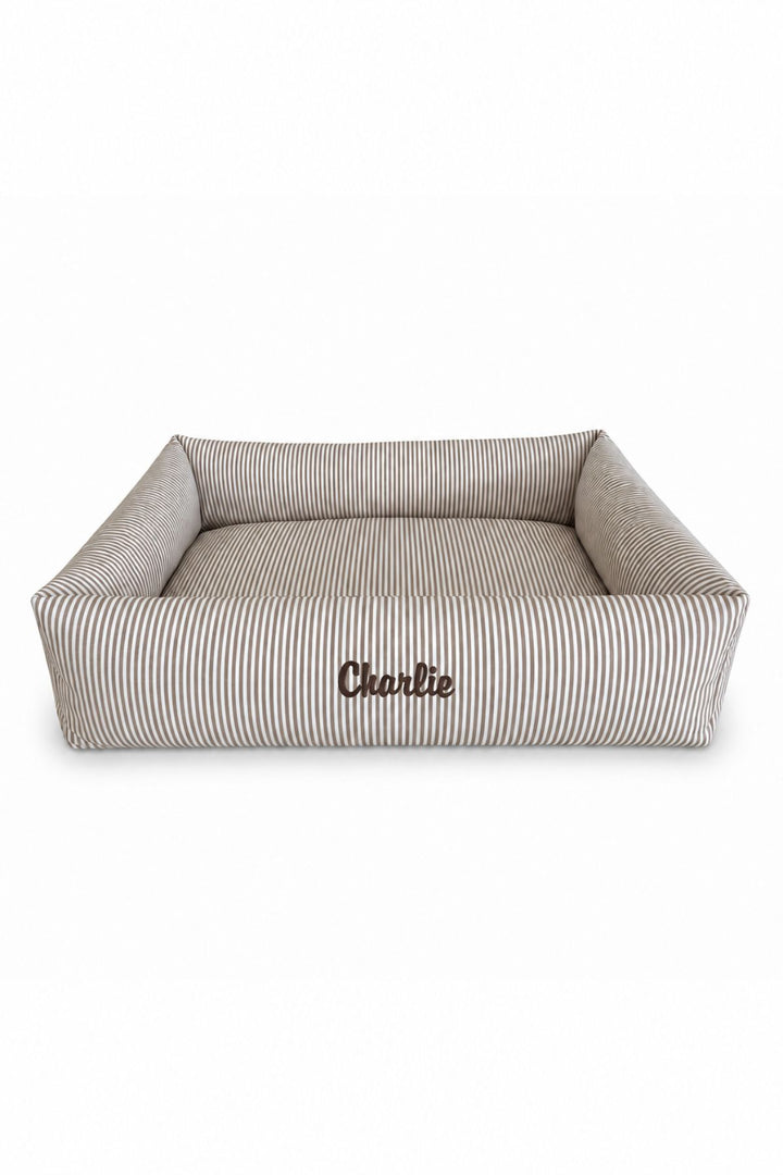 A rectangular high-sided Lane & Leash pet bed with a beige and white vertical stripe pattern, featuring the name 'Cherlie' embroidered on the front, set against a plain white background.