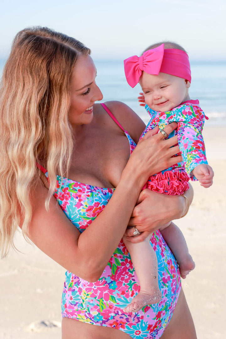mom holding baby on beach in petal splash matching swimsuits 