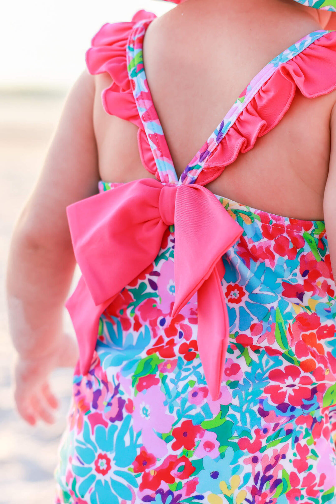 closeup of bright pink bow on petal splash double ruffle one piece for girls 