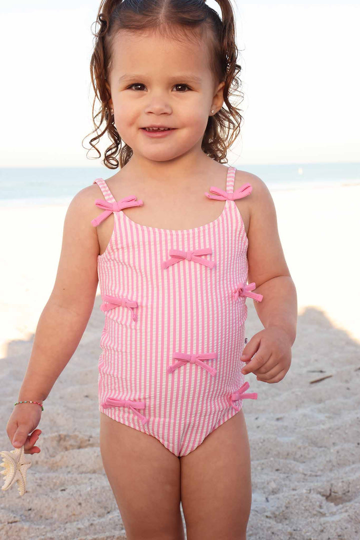 pink seersucker one piece swimsuit for girls with pink bows on the front 