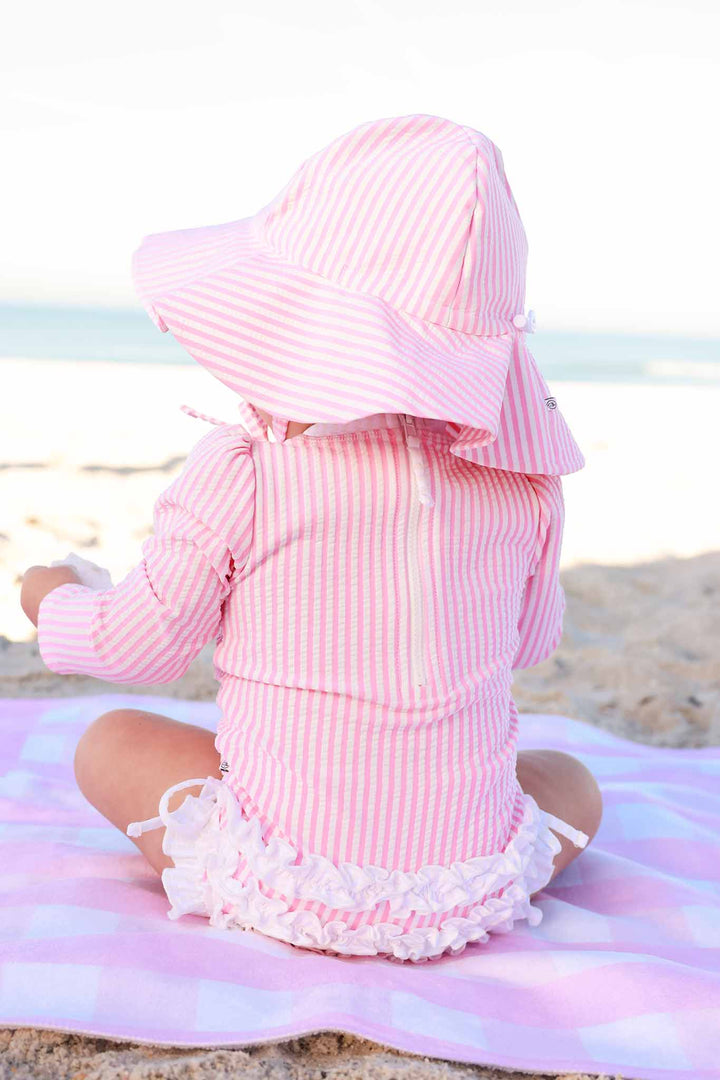back view of pink seersucker ruffle bottom rash guard swimsuit with matching hat 