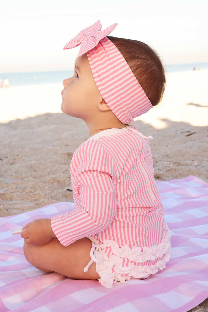 side view of pink seersucker ruffle bottom long sleeve rash guard swimsuit for girls 
