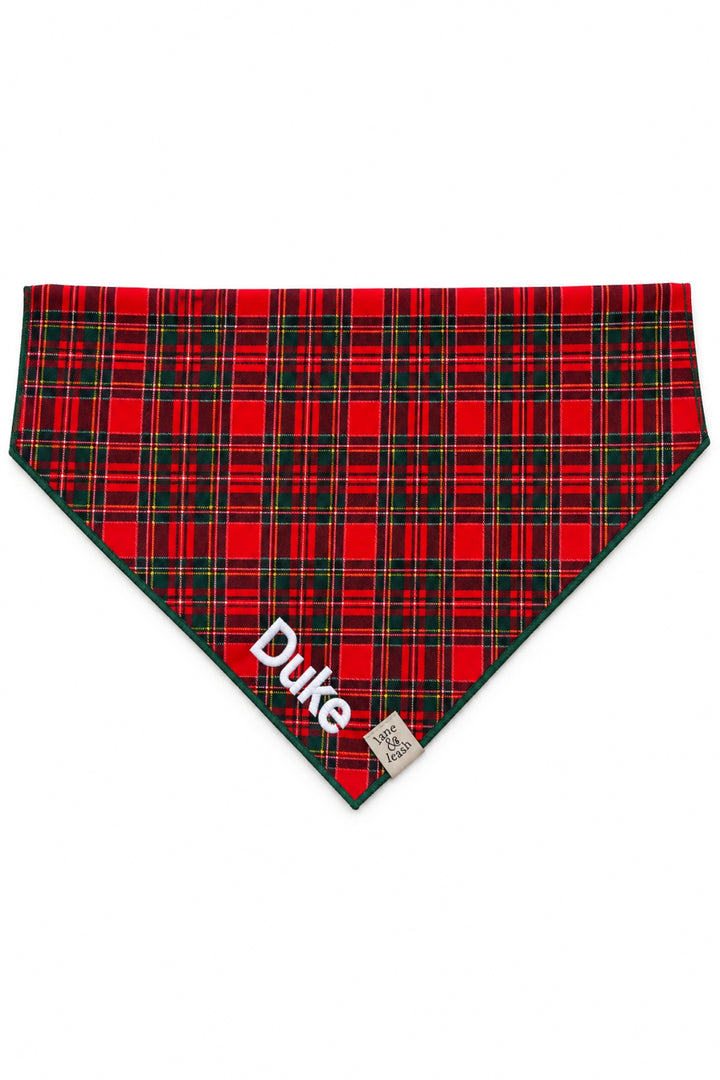 Lane & Leash personalized dog bandana in red tartan plaid with dark green edge trim, embroidered with the name 'Duke' in white